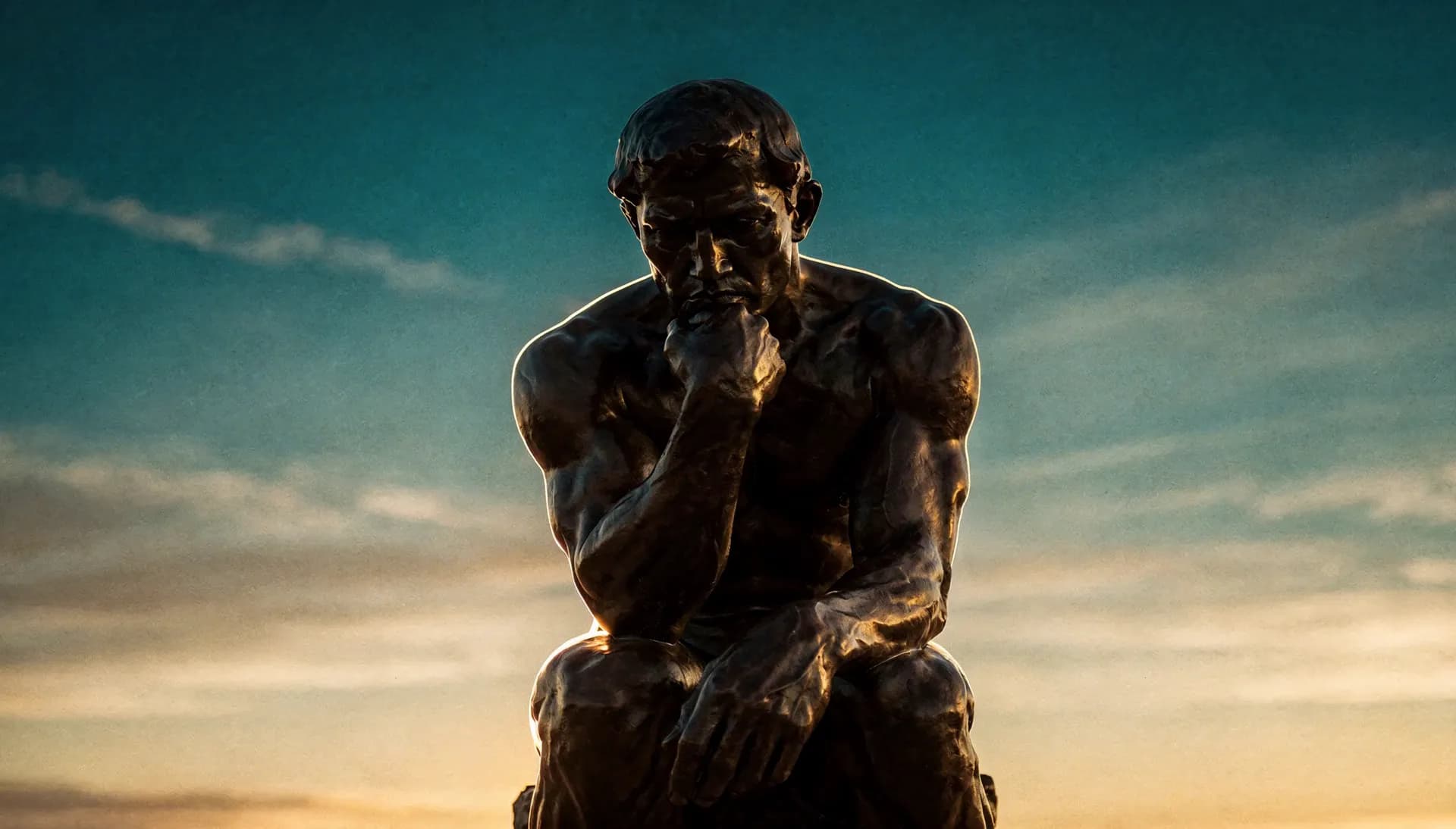 Rodin's Thinker, in bronze against a dusk sky, looks up from his thought and smiles