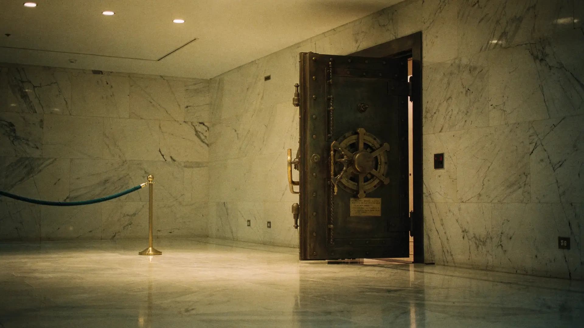 A heavy old bank vault door standing half open in a quiet, softly lit marble room